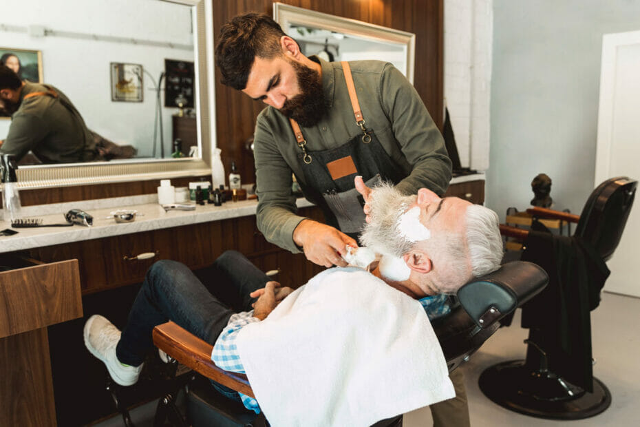 fazendo-a-barba-do-cliente-senhor-sentado-na-cadeira-do-serviço-de-corte-da-barbearia